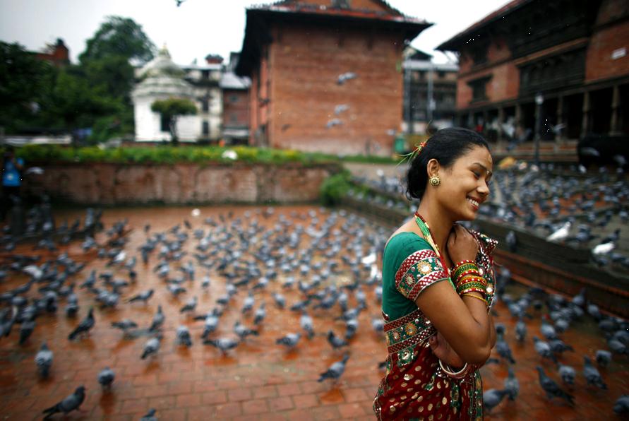 9月18日，尼泊尔加德满都，一名印度教女子在帕斯帕提那神庙做完提吉节祷告后从一群鸽子旁走过。 AP Photo/Niranjan Shrestha