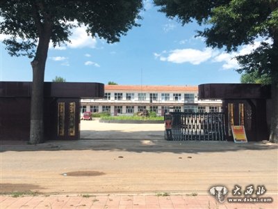 8月9日，文汇中学大门口已挂上乡政府四套班子的铭牌，白色建筑为文汇报捐资重建的主教学楼。新京报记者 林斐然 摄