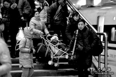 在春运站台上，两名旅客正在把婴儿车抬下楼梯。京华时报记者谭青摄